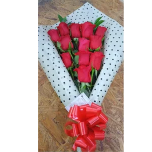 Bouquet engalanado de 12 rosas rojas envueltas en papel de lunares con moño rojo