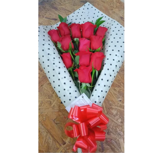Bouquet engalanado de 12 rosas rojas envueltas en papel de lunares con moño rojo