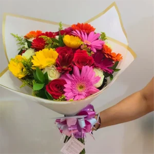 Bouquet radiante de 24 flores surtidas con rosas y gerberas coloridas envuelto en papel blanco con borde dorado