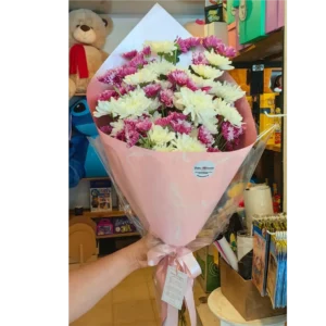 Bouquet de margaritas blancas y fucsias envuelto en papel rosado con lazo