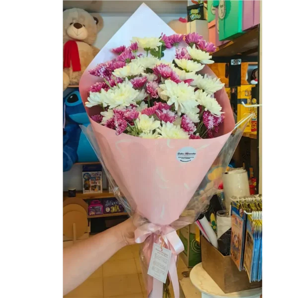 Bouquet de margaritas blancas y fucsias envuelto en papel rosado con lazo