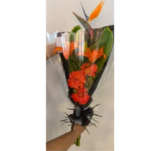 Ramo engalanado con aves del paraíso y gerberas naranjas en papel decorativo negro