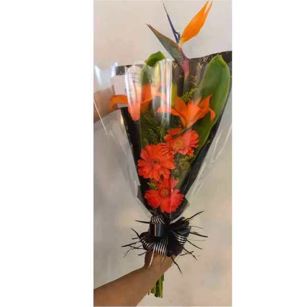 Ramo engalanado con aves del paraíso y gerberas naranjas en papel decorativo negro