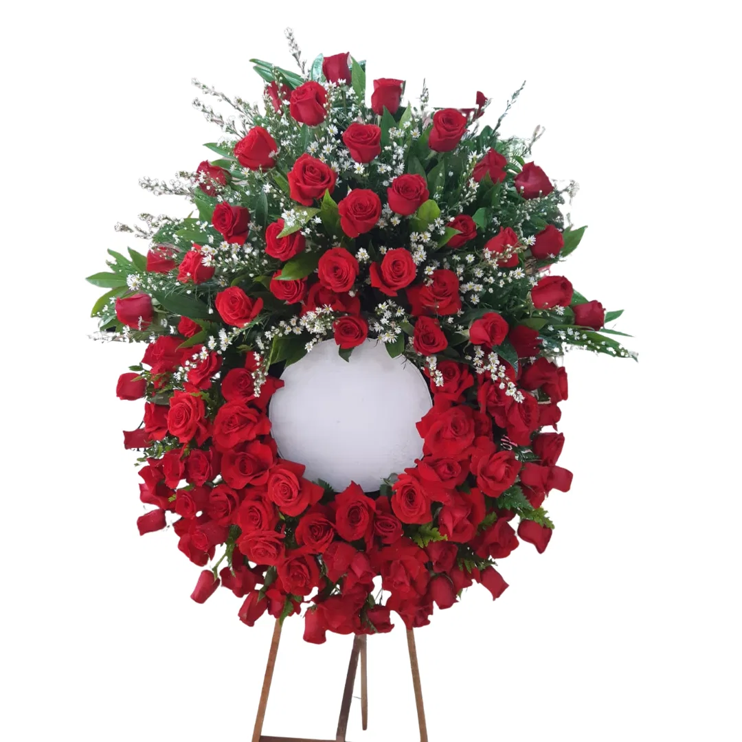Corona floral de condolencias con rosas rojas y follaje verde