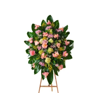 Arreglo floral de condolencias con flores rosadas y follaje verde