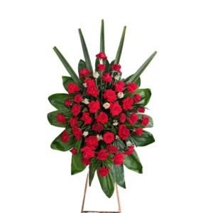 Arreglo floral de condolencias con rosas rojas y follaje verde